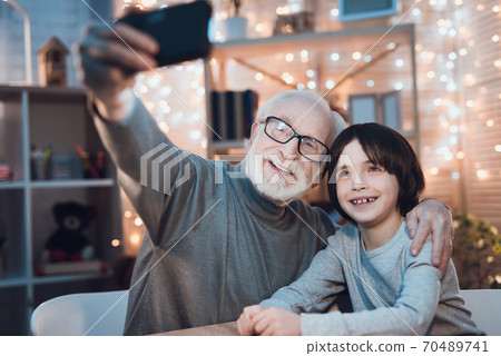 Boy smiles while grandfather makes memory photo. Boy smiles while grandfather makes memory photo. 70489741