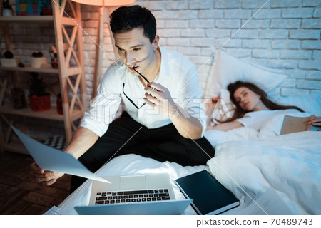 Husband works late at night while wife is sleeping Husband works late at night while wife is sleeping 70489743