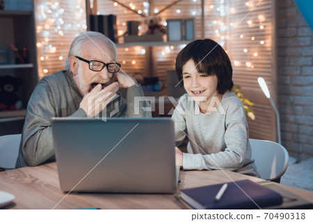 Grandson sits next to grandfather at home. 70490318