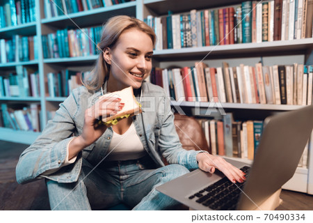 Student is eating sandwitch and using laptop. Student is eating sandwitch and using laptop. 70490334