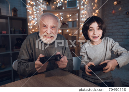 Grandfather and grandson are playing video games. Grandfather and grandson are playing video games. 70490338