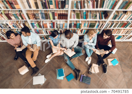 Students sitting in a library surrounded by books. Students sitting in a library surrounded by books. 70491785