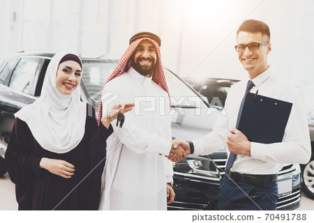 The seller shakes hands with the Arab in the car. 70491788