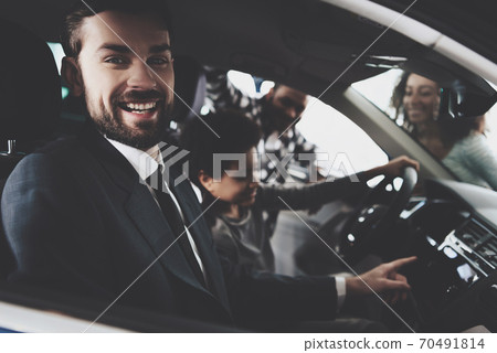 Man salesman sitting in a car in suit and smiling. 70491814
