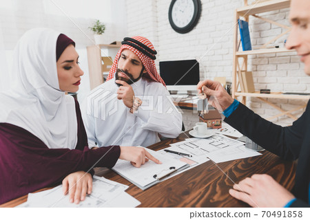 Realtor holds keys for a young couple of Arabs. Realtor holds keys for a young couple of Arabs. 70491858