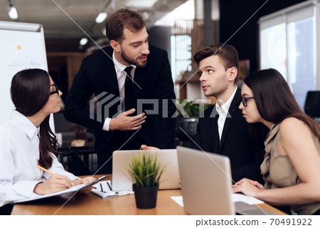 People sit at table and listen to their director. People sit at table and listen to their director. 70491922