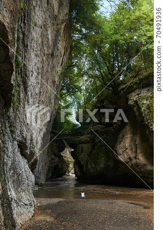 girl sitting on the river bank in a narrow rocky wooded canyon girl sitting on the river bank in a narrow rocky wooded canyon 70491936
