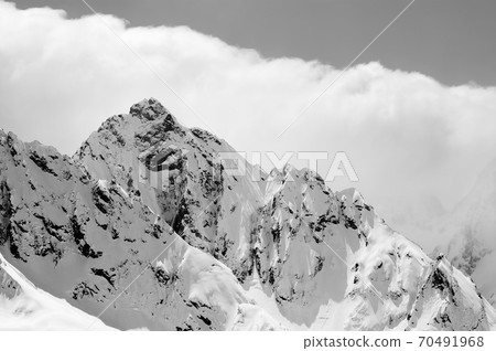 Snowy sunlit winter mountains in cloud Snowy sunlit winter mountains in cloud 70491968