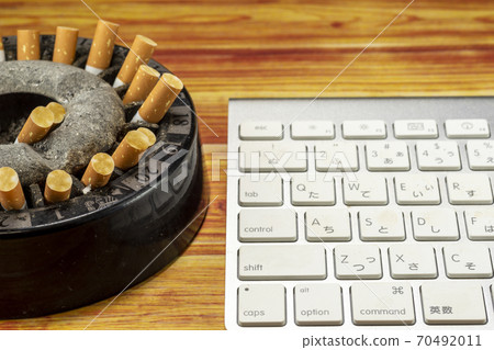 Ashtray full of butts and keyboard - Stock Photo [70492011]
