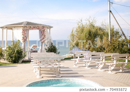 Beautiful wedding arch decorated by flowers with lake in background. 70493872