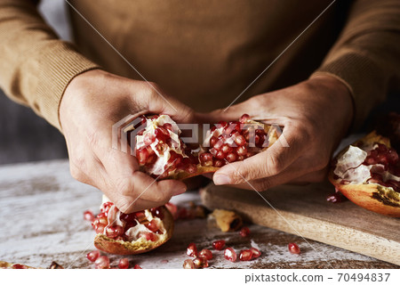 man opening a pomegranate fruit 70494837