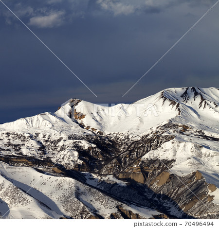 Winter mountains at sun evening and dark clouds Winter mountains at sun evening and dark clouds 70496494