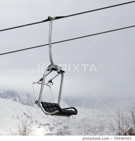 Chair lift and snowy mountains in haze Chair lift and snowy mountains in haze 70496563