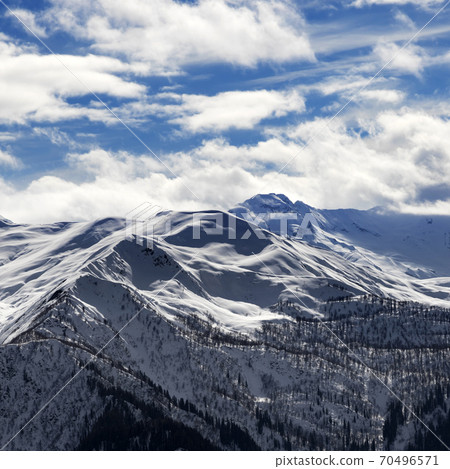 View on snowy mountains and cloudy sky in sun evening View on snowy mountains and cloudy sky in sun evening 70496571