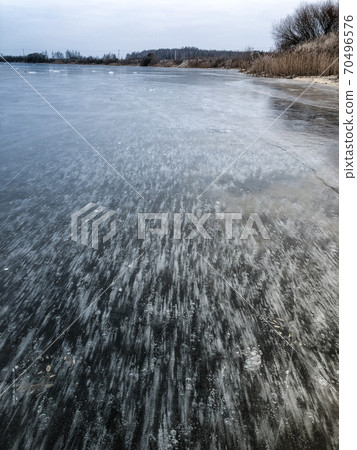 Winter landscape with icy air bubbles pattern in frozen lake surface Winter landscape with icy air bubbles pattern in frozen lake surface 70496576