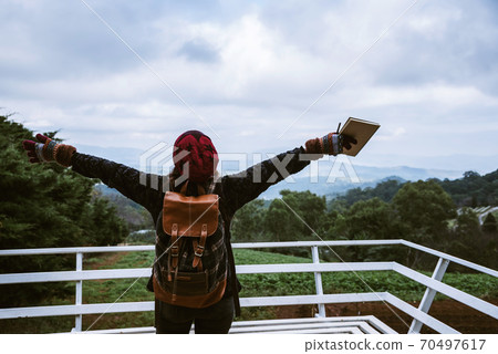 Asia young woman hold up both arms together with a note book on the peak mountains doi inthanon Asia young woman hold up both arms together with a note book on the peak mountains doi inthanon 70497617