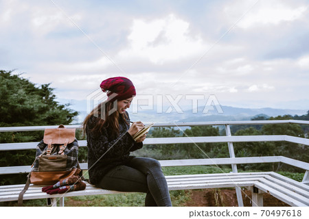 The girl is sitting relaxing at the natural mountain viewpoint and writing a record of her The girl is sitting relaxing at the natural mountain viewpoint and writing a record of her 70497618