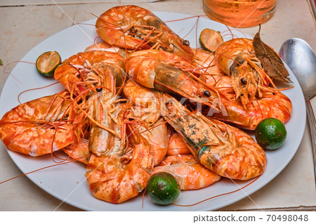 Red cooked prawns on a white plate with vegetables. 70498048