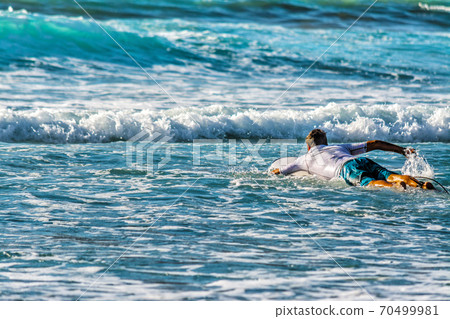 Surfer paddling to the line up Surfer paddling to the line up 70499981
