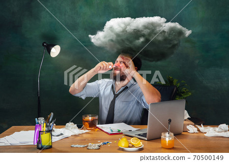 Ill young man with fever and cold looks suffering at home Ill young man with fever and cold looks suffering at home 70500149