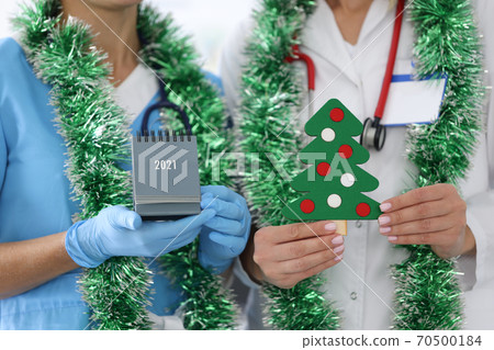 Nurse with white coat hold paper Christmas tree with decorations. 70500184