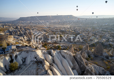 Scenic view of hot air balloons flying over stone formations in Cappadocia, Turkey. Scenic view of hot air balloons flying over stone formations in Cappadocia, Turkey. 70500329
