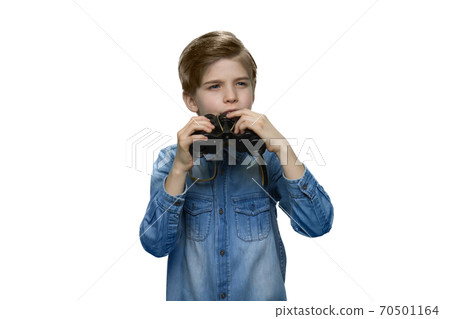 Little boy peering into distance and holding binoculars in his hands. 70501164