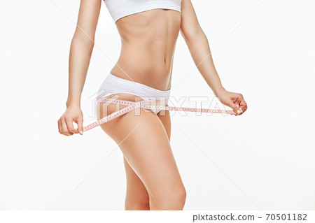 Slim tanned woman's body isolated on white background - waist measurement 70501182