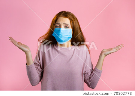 Unsure woman in medical mask shrugs her arms, makes gesture of I don't know, care, can't help Unsure woman in medical mask shrugs her arms, makes gesture of I don't know, care, can't help 70502778