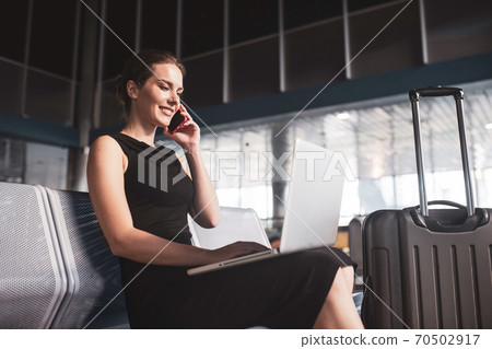 Woman talking on phone and surfing internet while travelling Woman talking on phone and surfing internet while travelling 70502917