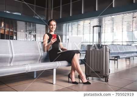 Business woman managing tasks while waiting for a flight Business woman managing tasks while waiting for a flight 70502919