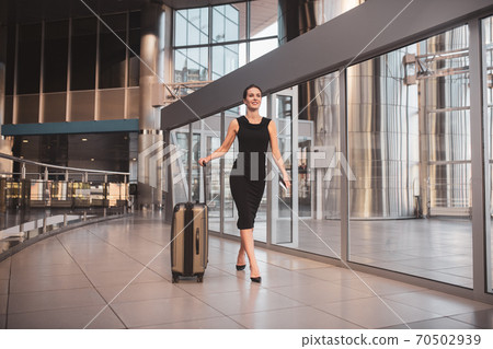 Woman carrying a large suitcase through the airport Woman carrying a large suitcase through the airport 70502939