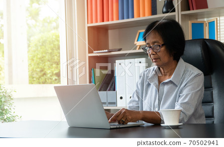 Happy senior Asian using the laptop for calculating and make a note of daily expenses. Concept of lifestyle, learning, and finance business 70502941