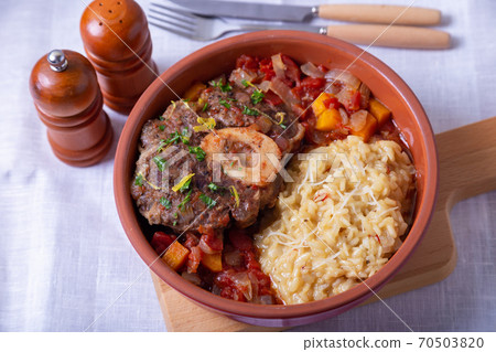Ossobuco. Veal (beef) shanks with saffron risotto in milanese, gremolata and sauce. Traditional Italian dish. Close-up. Ossobuco. Veal (beef) shanks with saffron risotto in milanese, gremolata and sauce. Traditional Italian dish. Close-up. 70503820