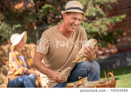 Male farmer standing on one knee, holding corn cobs 70503946