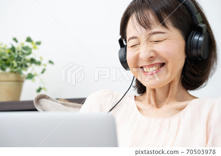 A woman wearing headphones and looking at a computer A woman wearing headphones and looking at a computer 70503978