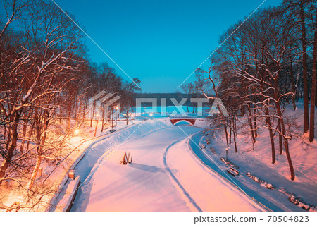 Gomel, Belarus. City Park In Winter Night. Old Bridge And Frozen Pond In Homiel Park, Belarus. Famous Local Landmark In Snow Gomel, Belarus. City Park In Winter Night. Old Bridge And Frozen Pond In Homiel Park, Belarus. Famous Local Landmark In Snow 70504823