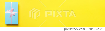 Christmas New Year birthday valentine celebration present romantic concept. Simply minimal design blue gift box isolated on yellow colorful background. Flat lay top view copy space, banner Christmas New Year birthday valentine celebration present romantic concept. Simply minimal design blue gift box isolated on yellow colorful background. Flat lay top view copy space, banner 70505235