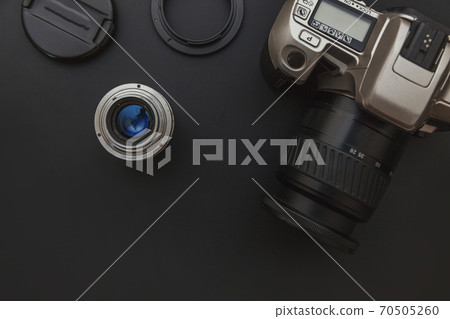 Photographer workplace with dslr camera system and lens on dark black table background. Hobby travel photography concept. Flat lay top view copy space. Photographer workplace with dslr camera system and lens on dark black table background. Hobby travel photography concept. Flat lay top view copy space. 70505260