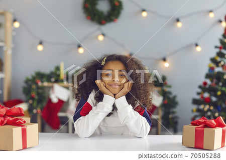 Happy girl sitting at table with presents during video call or while recording Christmas vlog 70505288