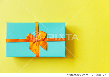 Christmas New Year birthday valentine celebration present romantic concept. Simply minimal design blue gift box isolated on yellow colorful background. Flat lay top view copy space. Christmas New Year birthday valentine celebration present romantic concept. Simply minimal design blue gift box isolated on yellow colorful background. Flat lay top view copy space. 70508174