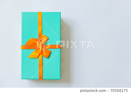 Christmas New Year birthday valentine celebration present romantic concept. Simply minimal design blue gift box with orange ribbon isolated on white background. Flat lay top view copy space. Christmas New Year birthday valentine celebration present romantic concept. Simply minimal design blue gift box with orange ribbon isolated on white background. Flat lay top view copy space. 70508175