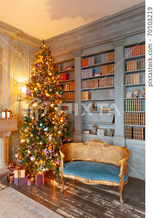Classic Christmas New Year decorated interior room home library with fireplace. Christmas tree with gold ornament decorations. Modern classical style interior design apartment. Christmas eve at home. Classic Christmas New Year decorated interior room home library with fireplace. Christmas tree with gold ornament decorations. Modern classical style interior design apartment. Christmas eve at home. 70508219