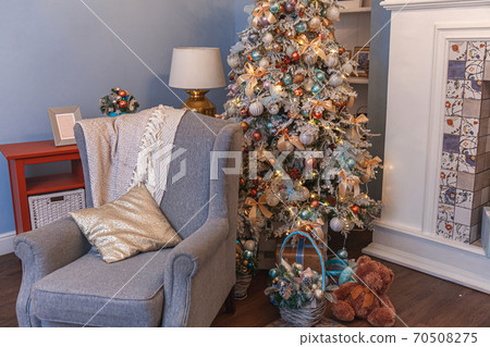 Classic Christmas decorated interior room, New year tree with silver decorations. Modern blue classical style interior design apartment with fireplace and armchair. Christmas eve at home. Classic Christmas decorated interior room, New year tree with silver decorations. Modern blue classical style interior design apartment with fireplace and armchair. Christmas eve at home. 70508275