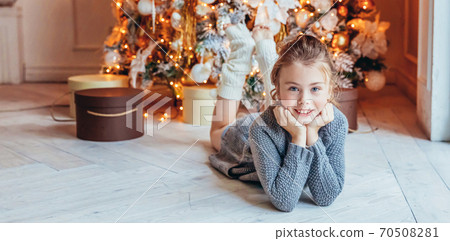 Little girl with gift box near Christmas tree on Christmas eve at home. Young kid in light bedroom with winter decoration. Christmas New Year december time for celebration concept. Banner Little girl with gift box near Christmas tree on Christmas eve at home. Young kid in light bedroom with winter decoration. Christmas New Year december time for celebration concept. Banner 70508281