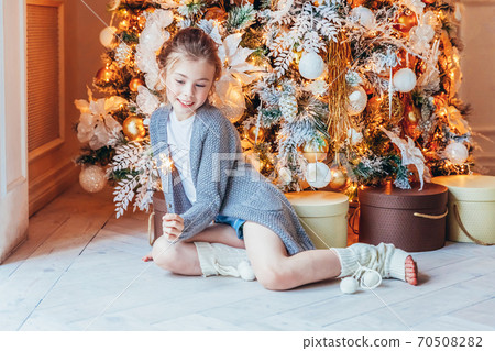 Little girl with sparkler near Christmas tree on Christmas eve at home. Young kid in light bedroom with winter decoration Happy family at home Christmas New Year december time for celebration concept Little girl with sparkler near Christmas tree on Christmas eve at home. Young kid in light bedroom with winter decoration Happy family at home Christmas New Year december time for celebration concept 70508282
