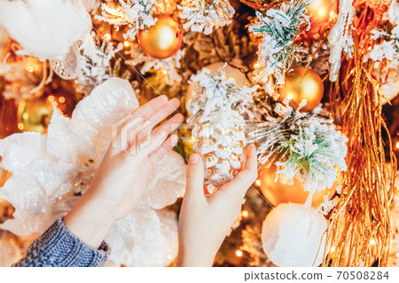 Close up girl hands decorating Christmas tree on Christmas eve at home. Young kid in light bedroom with winter decoration. Christmas New Year december time for celebration concept. Close up girl hands decorating Christmas tree on Christmas eve at home. Young kid in light bedroom with winter decoration. Christmas New Year december time for celebration concept. 70508284