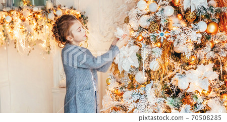 Little girl decorating Christmas tree on Christmas eve at home. Young kid in light bedroom with winter decoration. Christmas New Year december time for celebration concept. Banner Little girl decorating Christmas tree on Christmas eve at home. Young kid in light bedroom with winter decoration. Christmas New Year december time for celebration concept. Banner 70508285