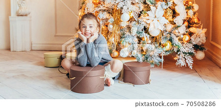 Little girl with gift box near Christmas tree on Christmas eve at home. Young kid in light bedroom with winter decoration. Christmas New Year december time for celebration concept Banner Little girl with gift box near Christmas tree on Christmas eve at home. Young kid in light bedroom with winter decoration. Christmas New Year december time for celebration concept Banner 70508286