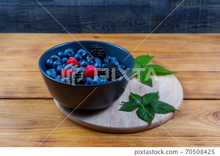 blueberry berry in dark gray ceramic bowl on dark blue wooden background. 70508425